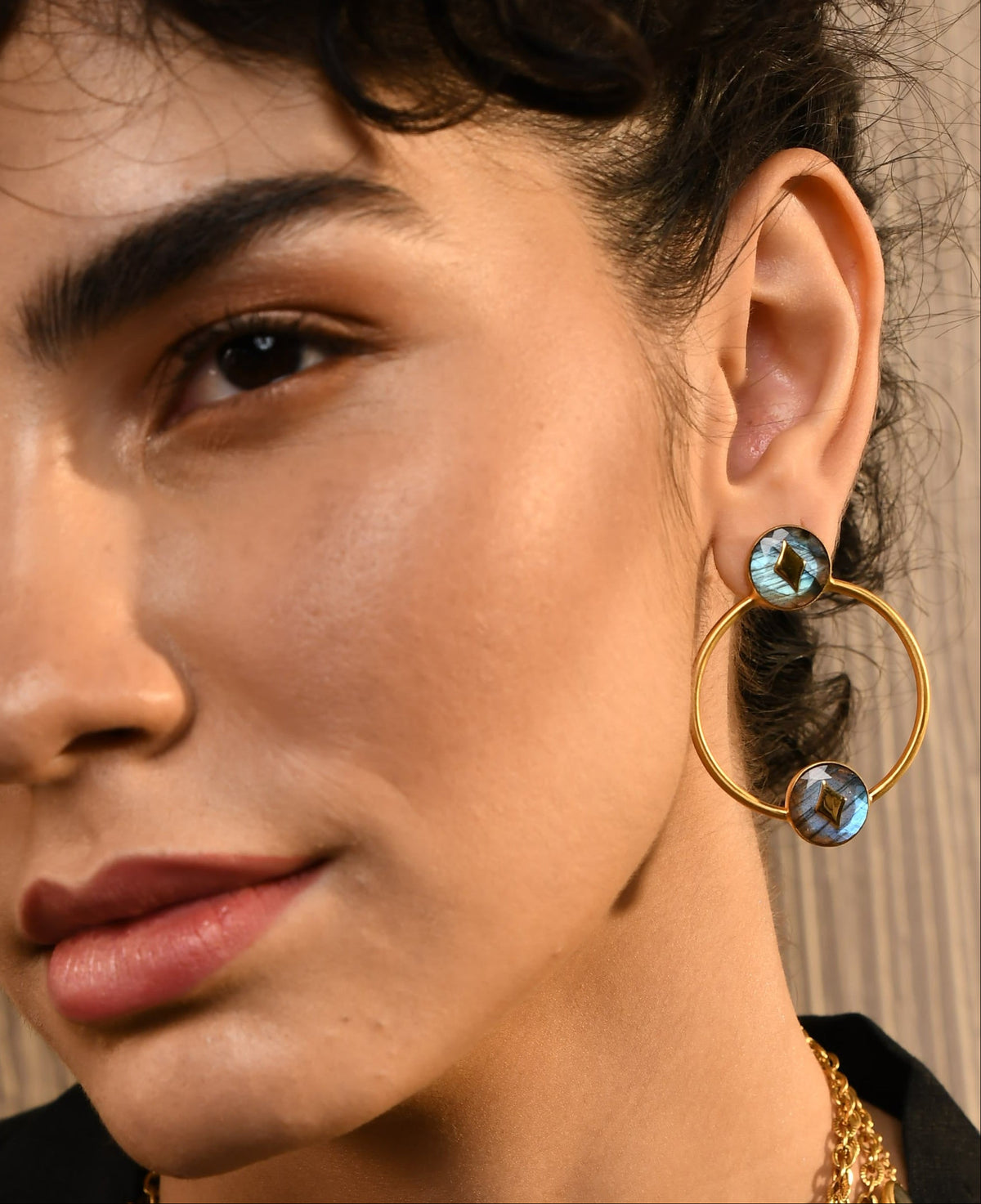 Close-up of a woman wearing gold hoop earrings .