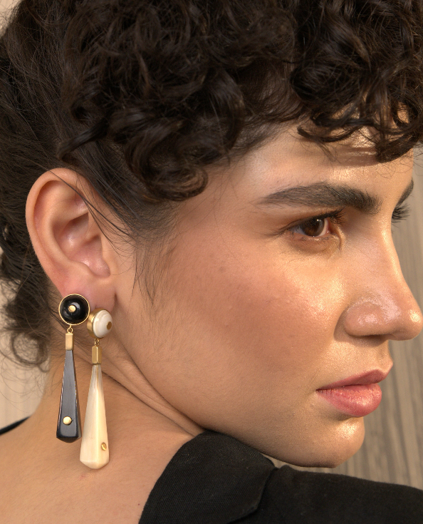 Close-up of a person wearing earrings with a neutral background