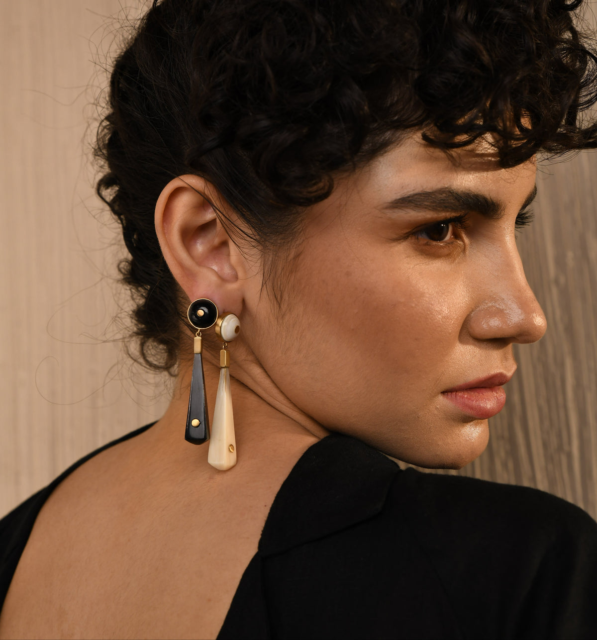 Close-up of a person wearing a unique earring with a black and gold design.