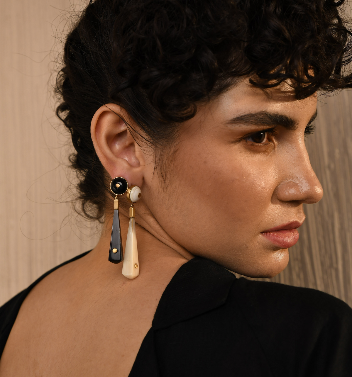 Close-up of a person wearing earrings with a neutral background