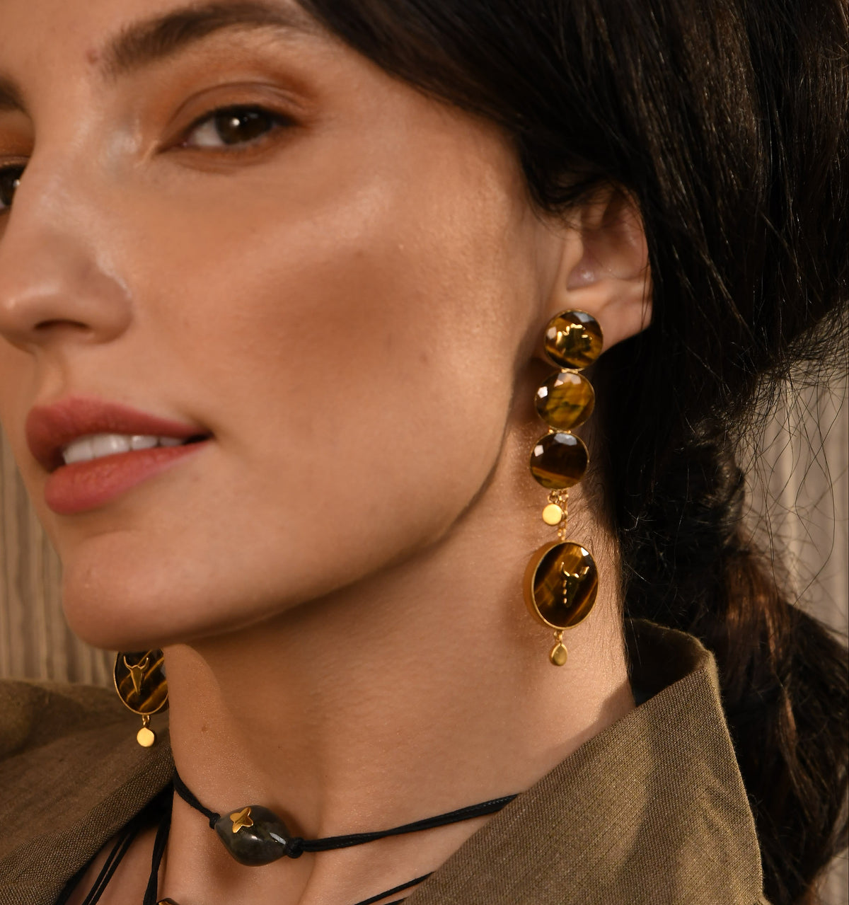 Woman wearing earrings and a necklace with a brown background.
