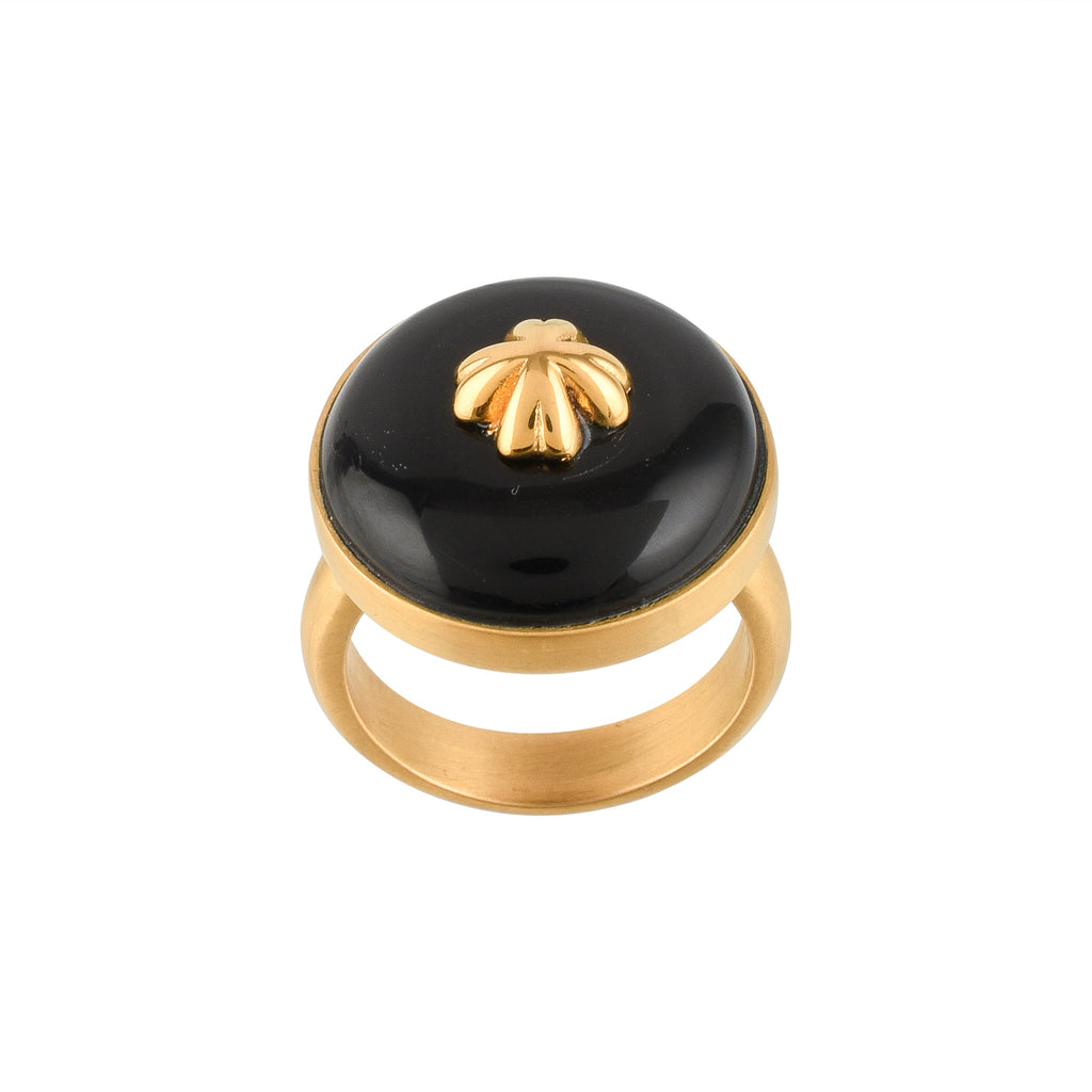 Gold ring with a black circular buffalo horn material and gold floral design on a white background