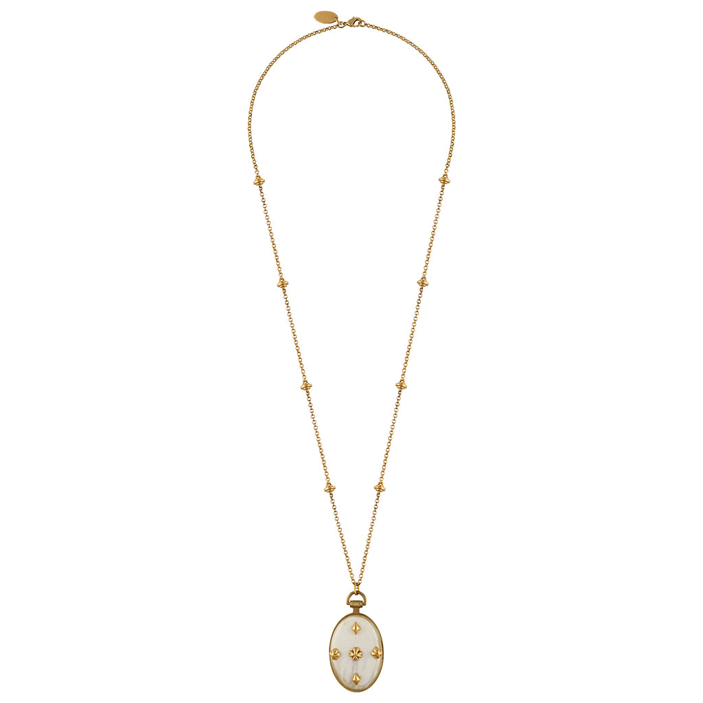 A gold chain necklace featuring a long drop pendant with a white enamel background and gold floral motifs, displayed against a solid white background.